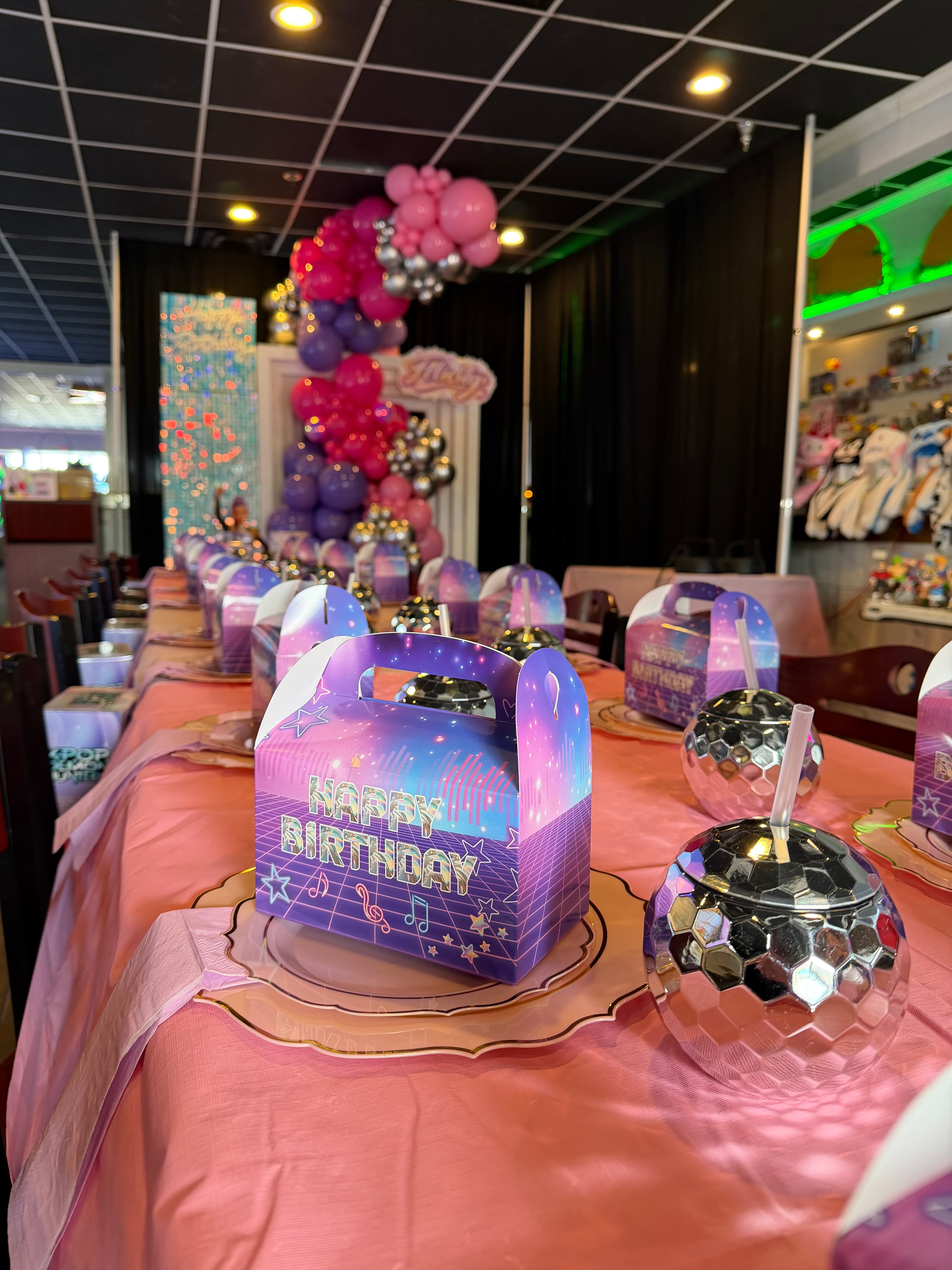 Birthday party setup with colorful balloons, themed boxes, and disco ball cups