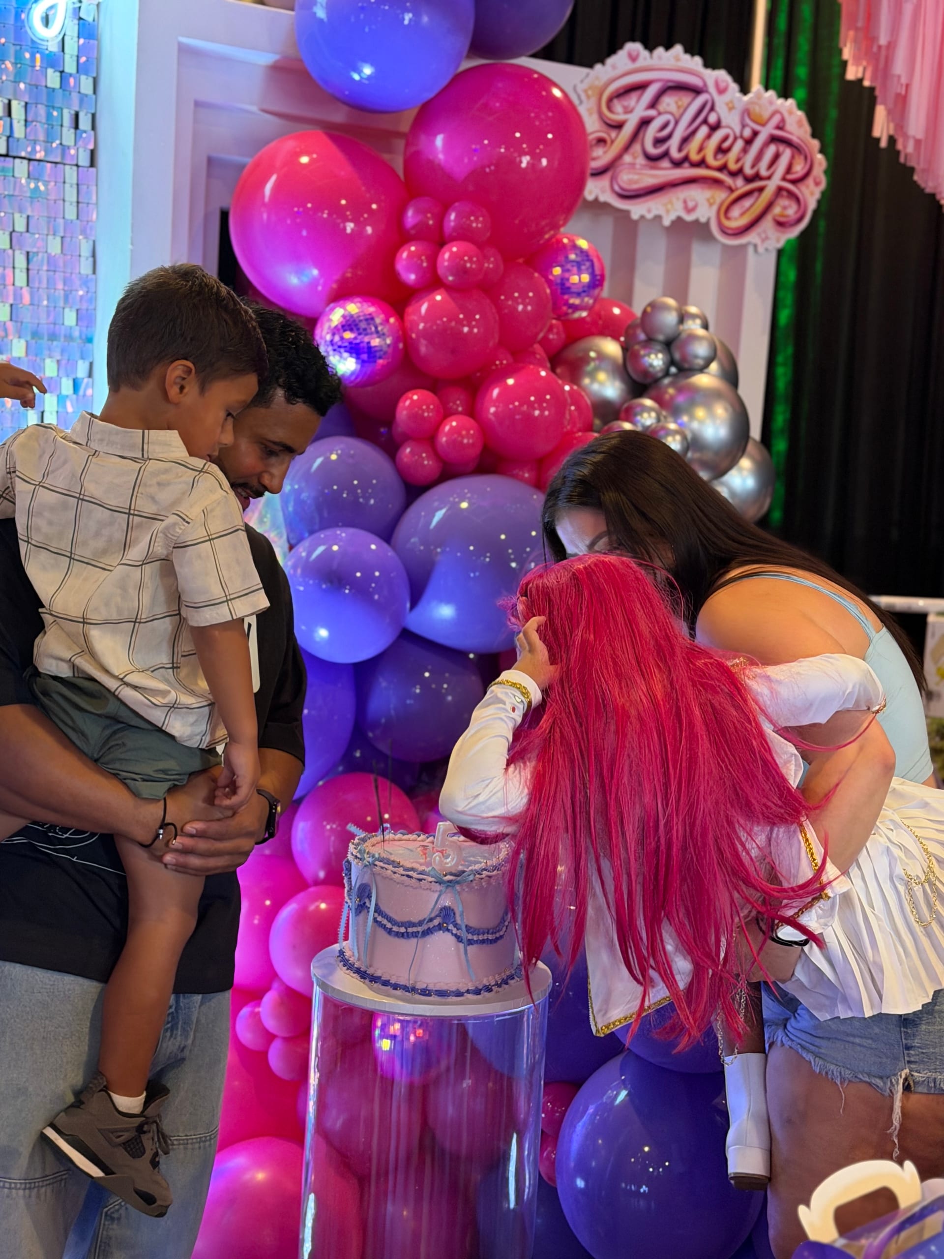 Family celebrating with birthday cake surrounded by balloon backdrop